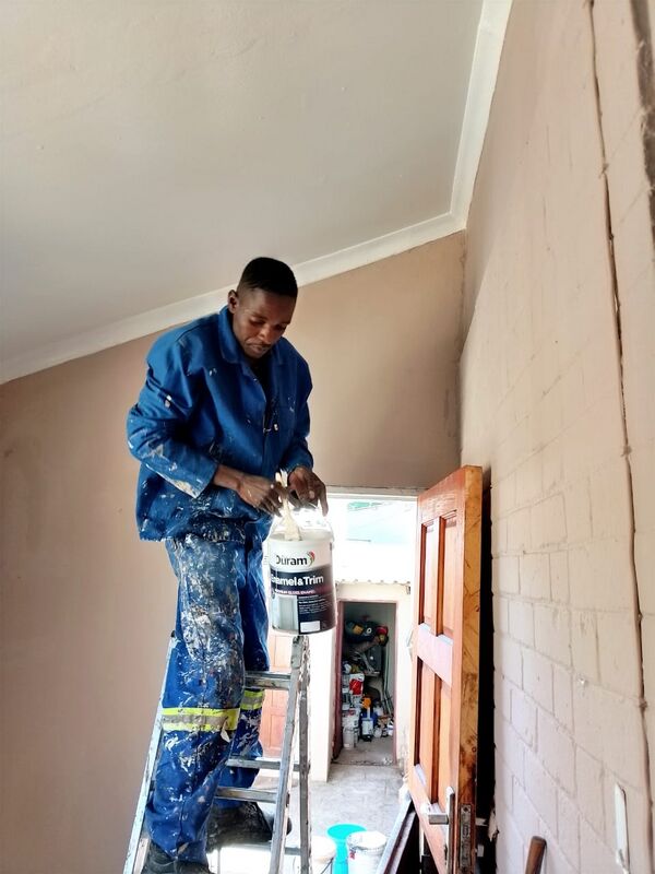 BlueGill painter in overalls on a stepladder with a tin of enamel paint, painting the room