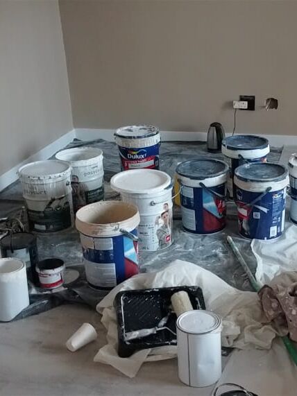 Room ready for painting, with the floor covered in drop sheets and paint tins grouped together